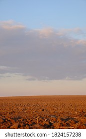 Cloudy Evening Sky Over An Empty Agricultural Field. Bright Sunset Landscape.