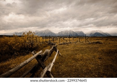 Cloudy fall morning view of the Tetons along a rustic fence from the historic J.P. Cunningham Cabin in Grand Teton National Park north of Jackson Hole Wyoming. 