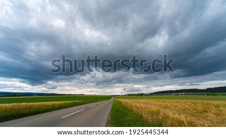 Cloudy landscape of the sky before the storm above country roads and fields