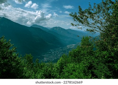 Cloudy mountain landscape. The gorge of the Caucasus mountains, with a small village below. tourist destinations. incredible landscape. mountainous terrain with lush vegetation and misty mountain tops