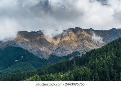 cloudy mountain range fronted by forests