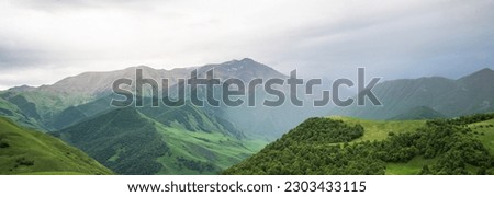 Cloudy and rainy day in spring, low storm clouds.Summer mountain landscape. Amazing view of the valley and lush green pastures in the Caucasus, Georgia. Valley surrounded by high mountain ranges.