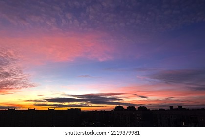 Cloudy rose blue sunset over dark silhouettes of city buildings, top view. Evening view. High quality photo
