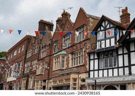 Cloudy skies over classic Tudor architecture and festive bunting in historic English town. Historic charm of stunning medieval houses and festive spirit while walking through picturesque Arundel.