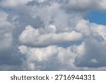 A cloudy sky with a blue sky in the background. The clouds are white and fluffy. The sky is mostly cloudy with a few clear patches