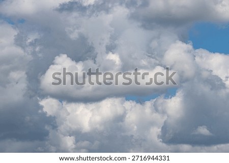 A cloudy sky with a blue sky in the background. The clouds are white and fluffy. The sky is mostly cloudy with a few clear patches