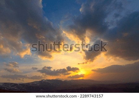 Cloudy sky. Dramatic sunset landscape with puffy clouds lit by orange setting sun and blue sky.