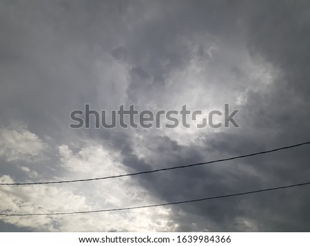cloudy sky with a little sunlight is enhanced by two wires passing through it. suitable for writing quots, backgrounds and more