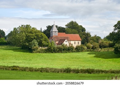 The cloudy sky over the field and old chapel with a weathervane on top of its tower