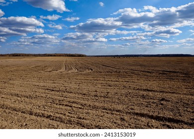 Cloudy sky over a large, empty, plowed field.