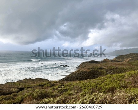 cloudy sky over ocean waves along a grassy cliffside