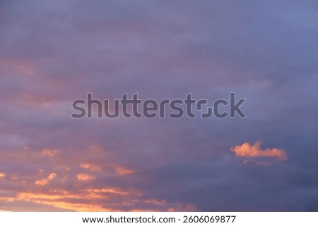 A cloudy sky with subtle hints of pink and orange, suggesting a sunset or sunrise. The overall tone is a soft, muted blue-gray.