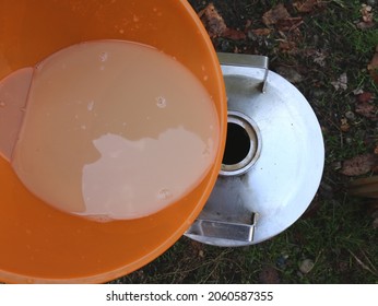 Cloudy Strained Apple Puree In An Orange Bowl, Poured Into The Stainless Steel Tank Hole Of The Moonshine Still, Part Of The Process Of Making A Homemade Alcoholic Drink From Fruit