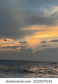 cloudy sunset at the beach featuring the ocean.