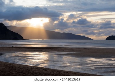 Cloudy sunset with a large spotlight of sunlight.