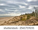 Cloudy Winter landscape of an empty beach beside sand dunes along the Lake Michigan shoreline at Point Beach State Forest near Two Rivers, Wisconsin.
