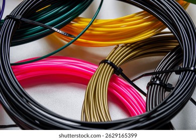 Clouse-up view of multiple coils of 3Dprinter filament in various vibrant colors, neatly arranged on a white surface.The photo highlights the diversity of filament types and colors used in 3D printing
