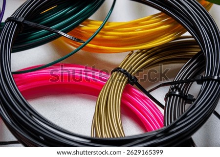 Clouse-up view of multiple coils of 3Dprinter filament in various vibrant colors, neatly arranged on a white surface.The photo highlights the diversity of filament types and colors used in 3D printing