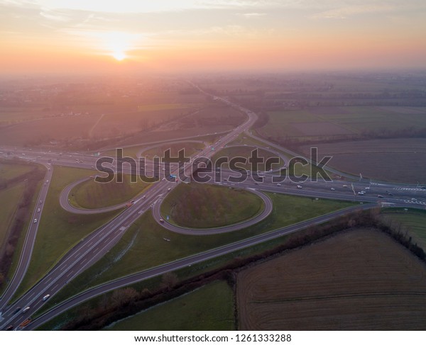 Cloverleaf interchange seen from above. Aerial view\
of highway road junction in the Po valley near Milan at sunset.\
Bird\'s eye view.