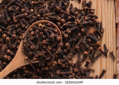 The cloves are on the spoon and spread on the ground.