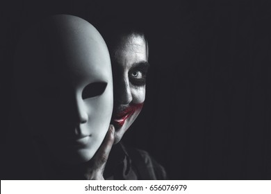 clown hiding his self behind anonymous white mask - Shutterstock ID 656076979