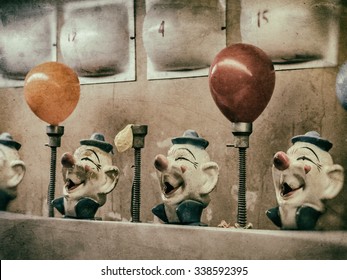 Clown Water Gun Game Vintage. A classic water gun clown balloon carnival game. Old, aged clown heads and numbered flashing lights. Squirting and balloons inflating. Edited with a vintage film effect.