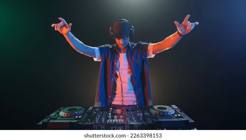 Club, disco DJ playing and mixing music for crowd of happy people. Nightlife, concert lights, flares - Powered by Shutterstock