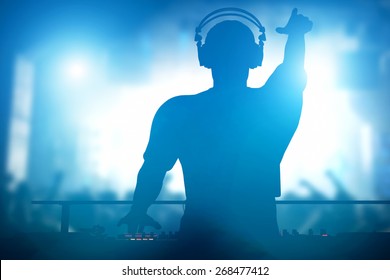 Club, disco DJ playing and mixing music for crowd of happy people. Nightlife, concert lights, flares - Shutterstock ID 268477412