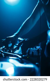 Club dj mixing music set on party in bright blue lights. Silhouette of disc jockey on stage