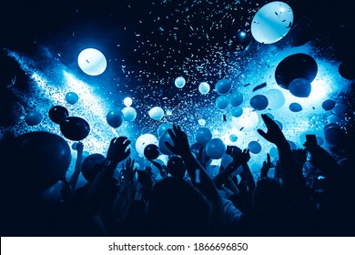 Club party. Silhouettes of concert crowd in front of bright stage lights and confetti. 