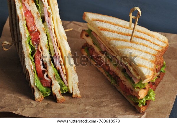 Club\
sandwich with bacon and ham on kraft paper. The sandwich is divided\
in half into two triangles. The sandwich is made from white bread,\
fried on a grill. Close-up. Macro\
photography.