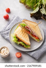 Club Sandwich On A Blue Plate And Napkin Of Ham Cheese, Cucumber, Tomato And Lettuce Leaves Close-up On A Blue Background With Mayonnaise. 