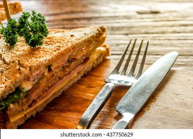 Club Sandwich On The Wood Plate Decorate Together With Fork And Knight On The Bark Wood Table Background