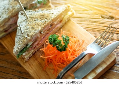 Club Sandwich On The Wood Plate Decorate With Chopped Carrot And Parsley Together With Fork And Knight On The Bark Wood Table Background