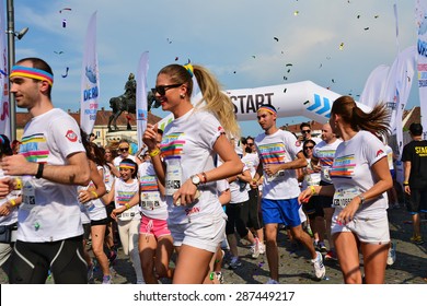 CLUJ-NAPOCA, ROMANIA - JUNE 13, 2015: Unidentified Color Run Runners of all ages and genders wearing colorful t-shirts and headbands take off from the starting line as the race begins.