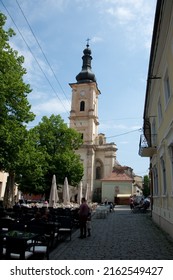 CLUJ-NAPOCA, ROMANIA - MAY 3, 2014: Cluj-Napoca Franciscan Church, At The End Of Museum Square. Table And Chairs Are Set Up On The Square For Outdoor Dining