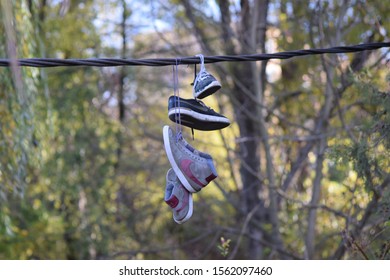 CLUJ-NAPOCA, ROMANIA - November 9, 2019:  Shoes And Pairs Of Sneaker Tied Together And Hanging From A Rope. Shoes On A Wire. Untangling An Urban Myth.