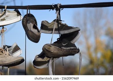 CLUJ-NAPOCA, ROMANIA - November 9, 2019:  Shoes And Pairs Of Sneaker Tied Together And Hanging From A Rope. Shoes On A Wire. Untangling An Urban Myth.