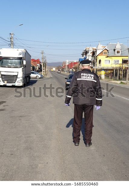 Cluj-Napoca,Cluj/Romania-03.26.2020:Police officer\
from the local police in Romania checks a vehicle during COVID 19\
pandemy.All citizen from Romania must stay inside in order to\
prevent the\
spread