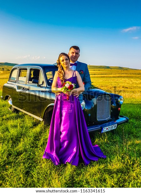 Cluj-Napoca,Romania-August 18,2018:Photo session\
with a couple of newly married,groom and bride near a london taxi.3\
photographers take a photo session to the wedding couple, trash the\
dress.
