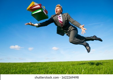 Clumsy Businessman Tripping Dramatically Outdoors With His File Folders In A Green Grass Meadow