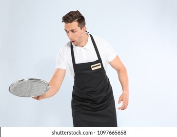 Clumsy Waiter Dropping Empty Tray On Light Background