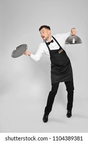 Clumsy Waiter Dropping Empty Tray On Light Background