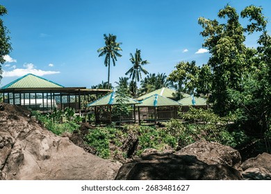 Cluster of eco-huts with coconut trees in the background, set in a lush tropical landscape.