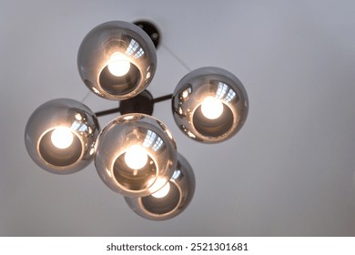 A cluster of lights hanging from the ceiling. The lights are all on and are evenly spaced. The lights are all the same color and are all turned on