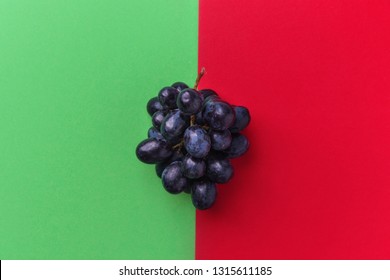 Cluster of moon drops dark purple grapes on duotone red green background. Wine production harvest vitamins healthy lifestyle concept. Creative food poster with copy space