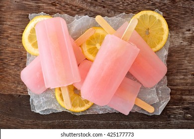 Cluster Of Pink Lemonade Popsicles On Wax Paper With Rustic Wood Background