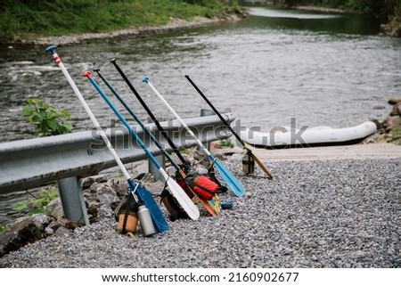 A cluster of whitewater rafting and canoeing paddles, rope bags, water bottles, and gear for rafting down a rapid river through the Smoky Mountains.