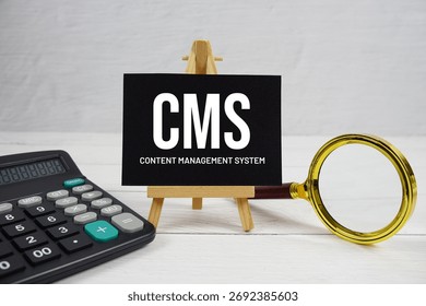 CMS abbreviation of Content Management System text with magnifying glass and calculator on wooden background