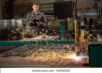 CNC Laser Plasma. Selective Focus On Laser Plasma Cutting Of Metal Modern Technology In Process At Metalworking Manufacturing Plant Male Worker On The Background Copyspace 